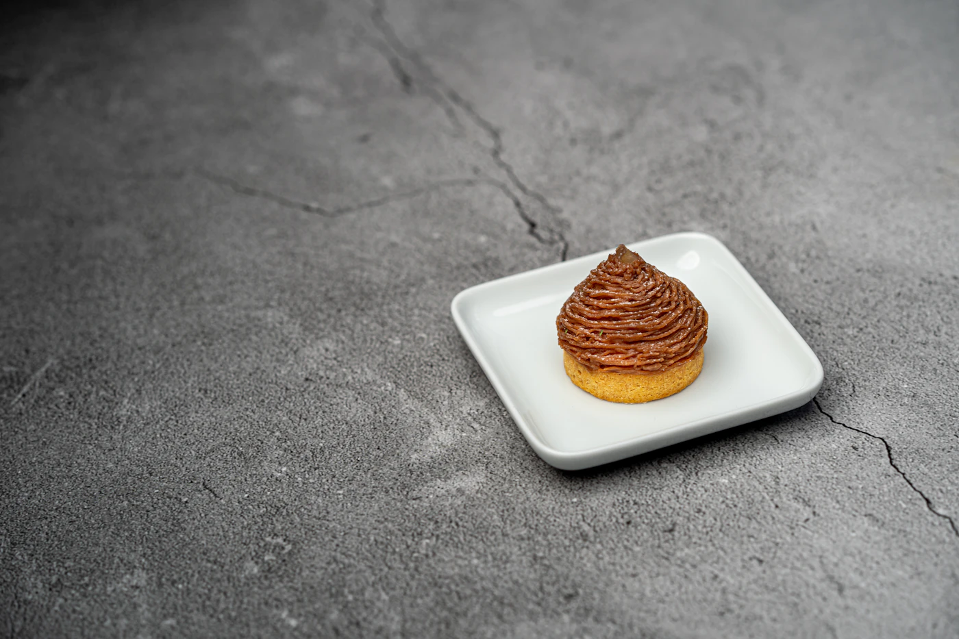 A single choux with a piped crown, standing on scratched grey stone.