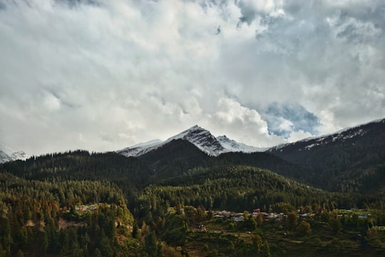 aerial photography of houses on green field viewing mountain uner white sky in Bhuntar India