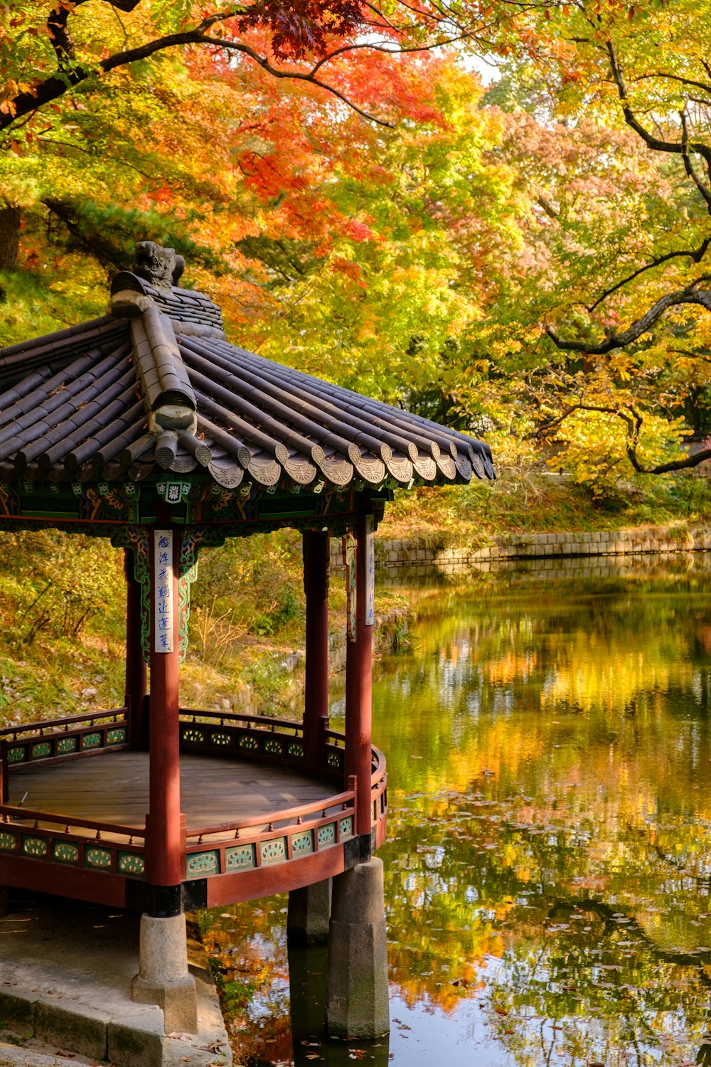 red and black temple beside lake