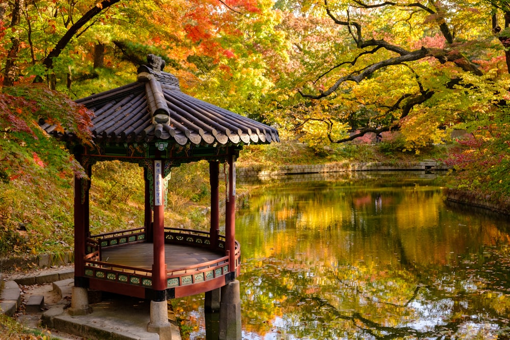 red and black temple beside lake