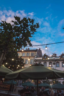 A vibrant outdoor plaza at Vibo Place bustling with shoppers and diners under string lights at dusk.