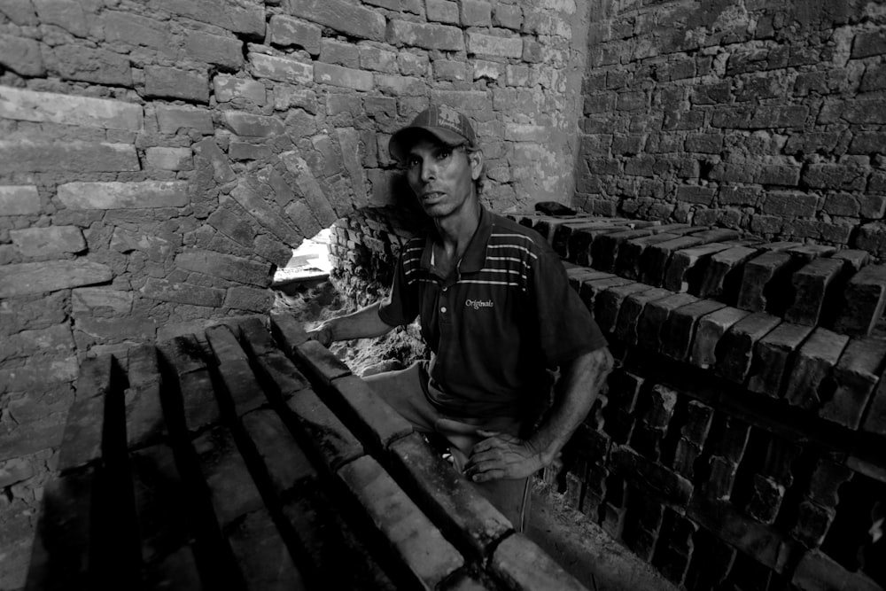 man sitting near bricked wall