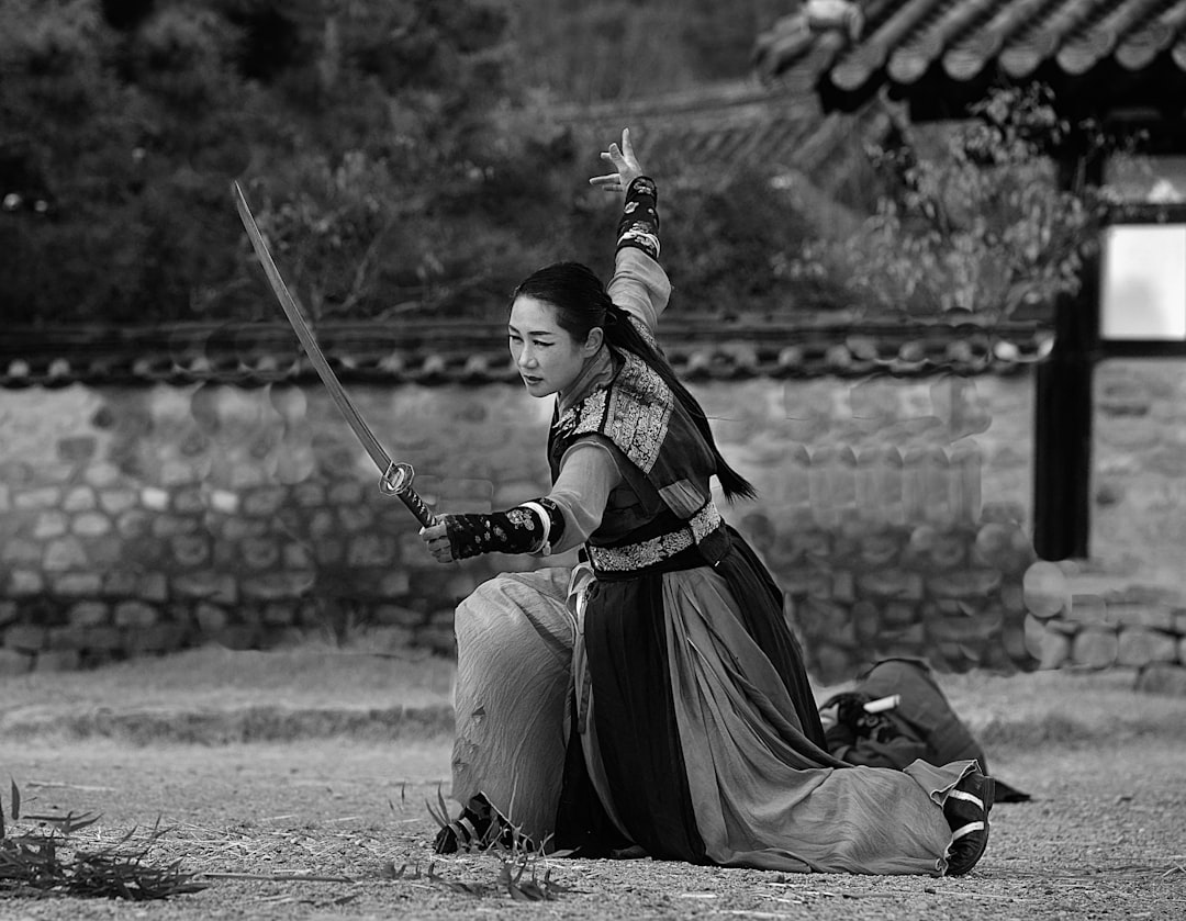 grayscale photo of woman holding sword,
