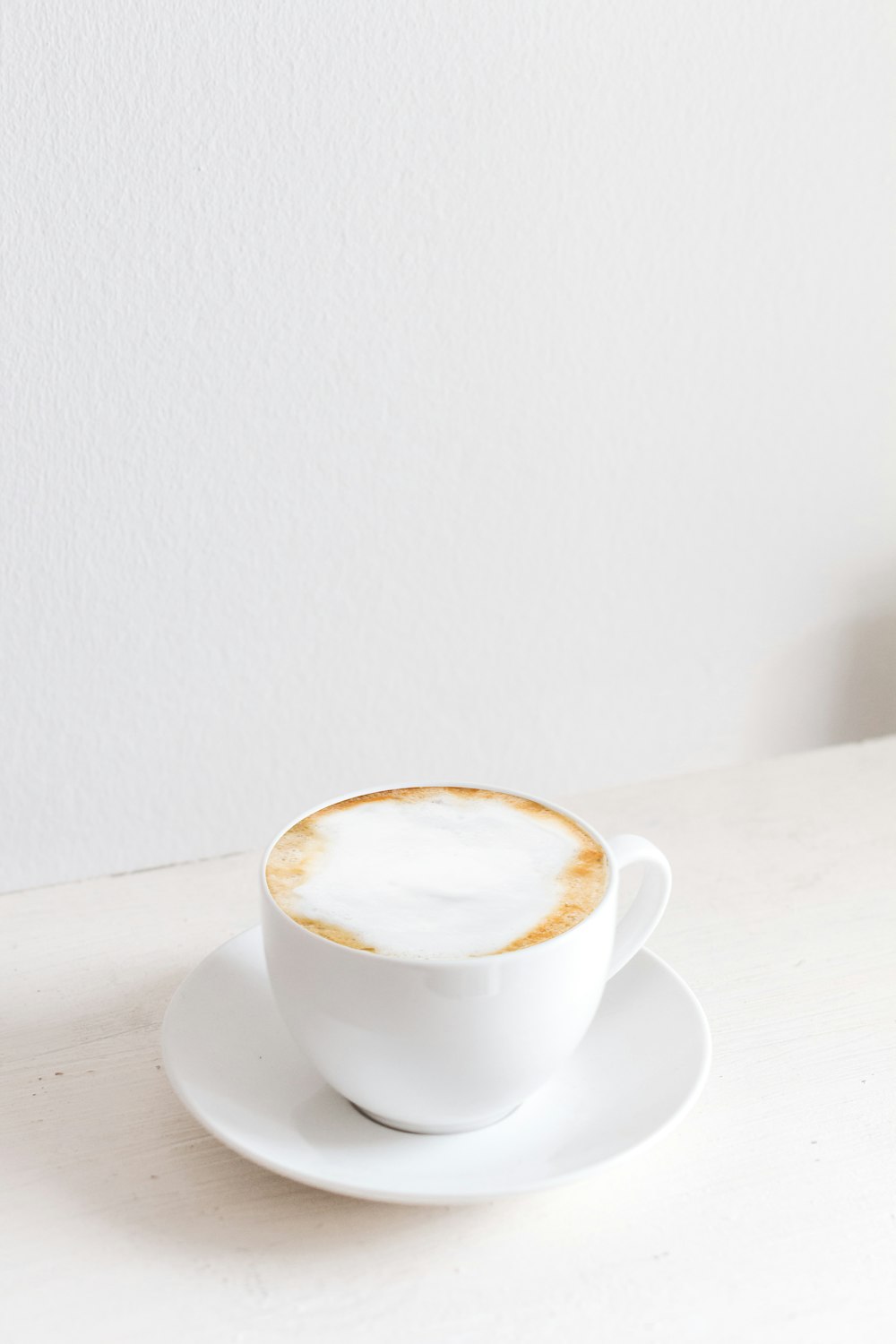 white mug with saucer on white surface