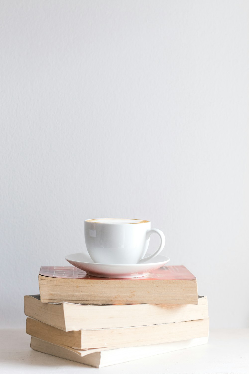 white mug with saucer on piled books