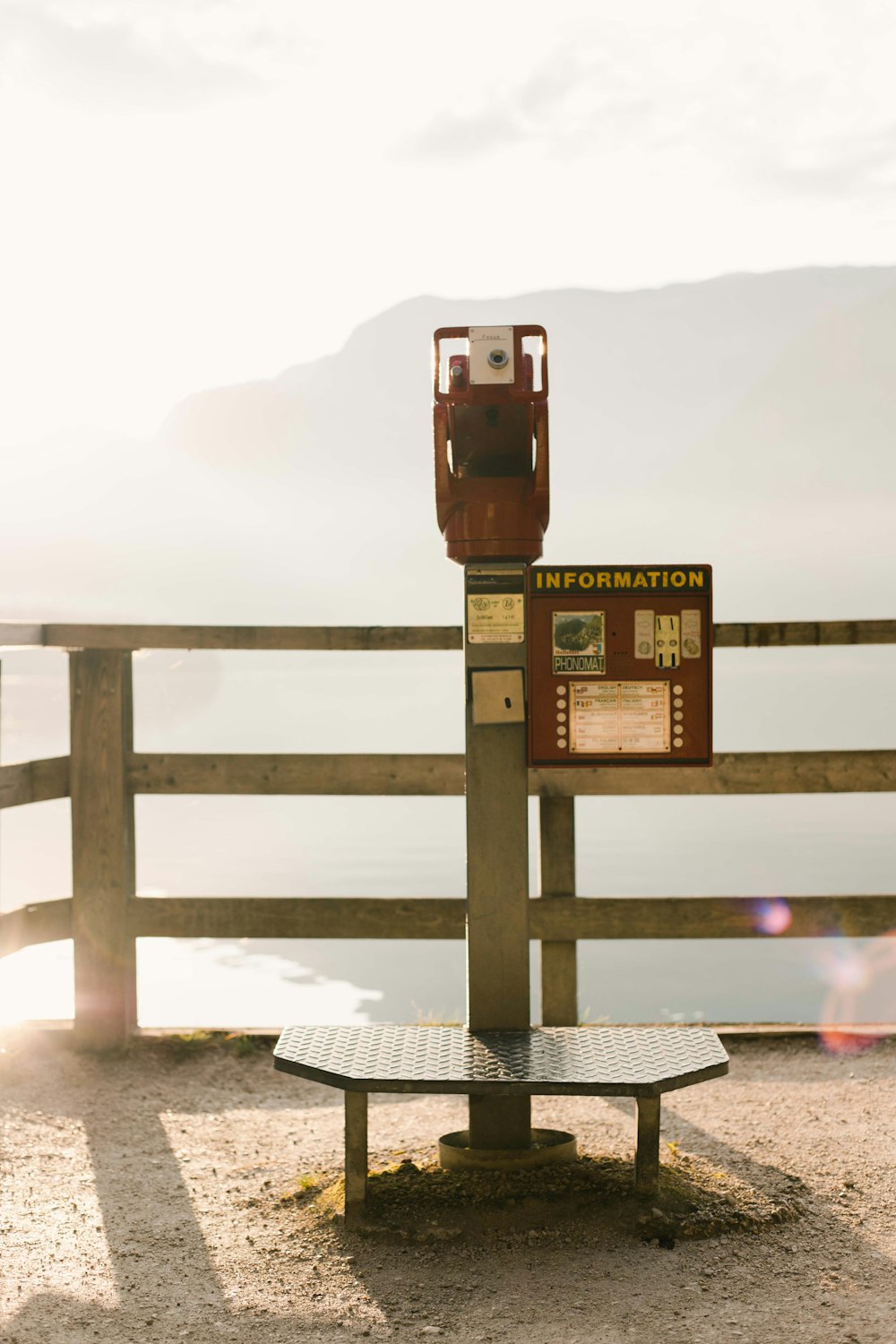 brown and gray coin-operated telescope near gray wooden railings viewing mountain