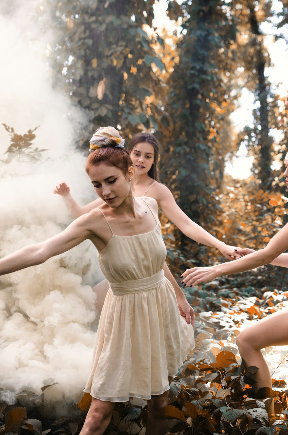 three women dancing near tall trees with white fogs