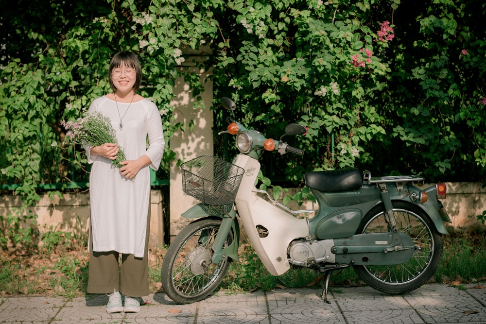 smiling woman holding flowers standing beside park motorcycle