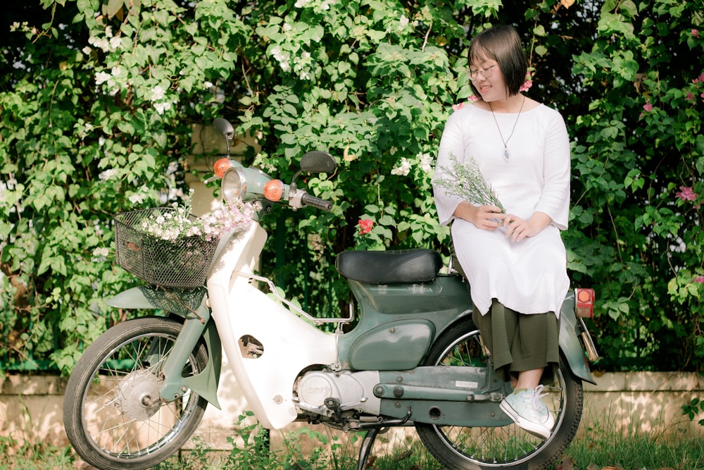 woman wearing white dress sitting on motor scooter seat