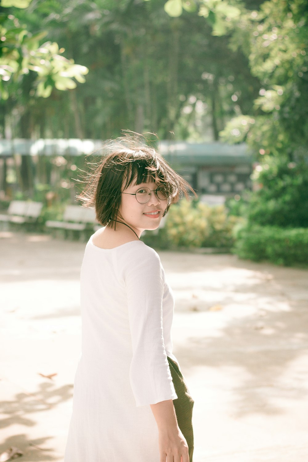 woman wearing white dress looking back while walking on street