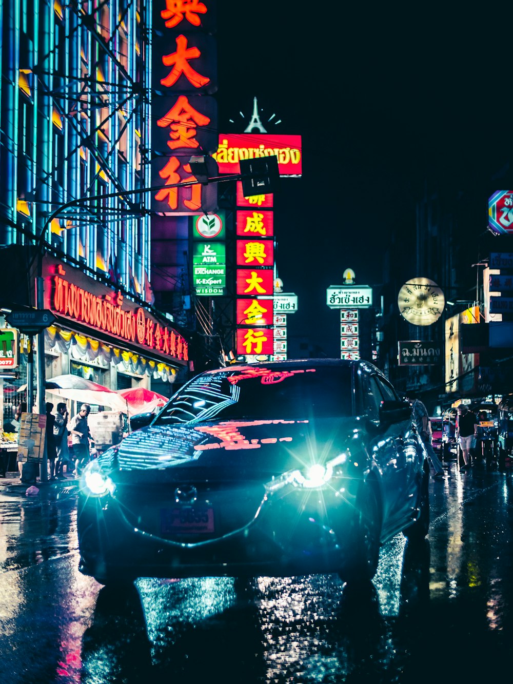 gray Mazda sedan on road viewing buildings during night time