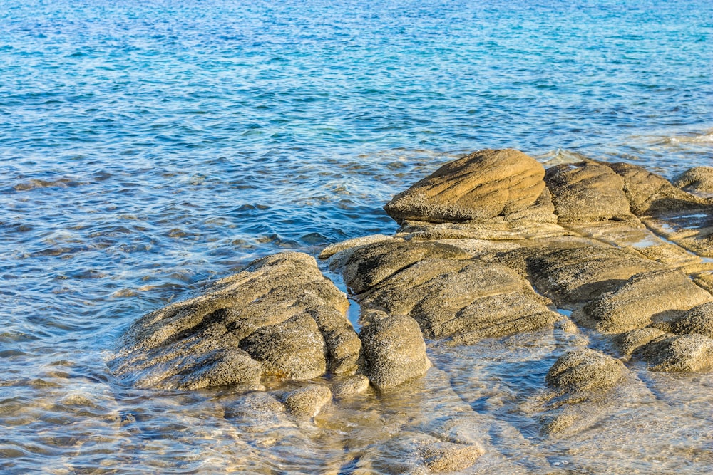 brown rock formations on blue body of water