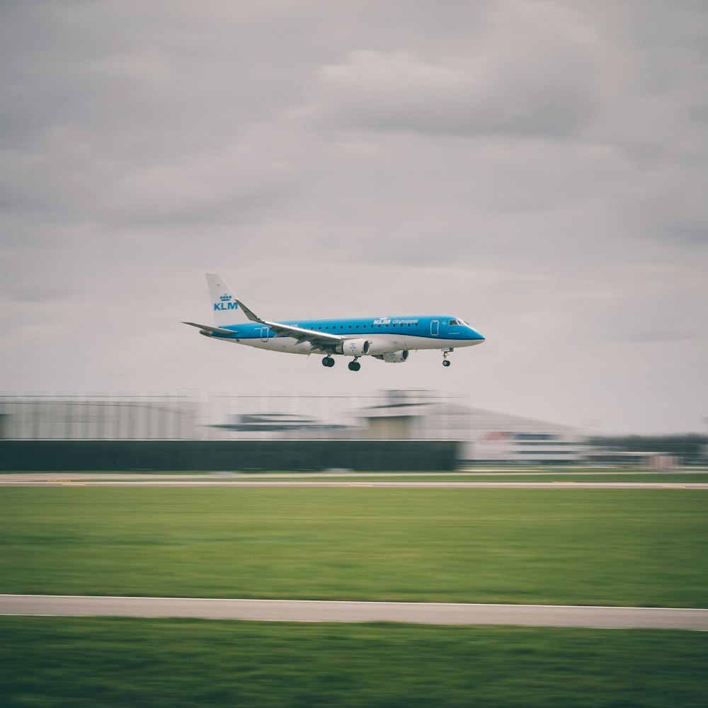 avión de pasajeros blanco y azul sobre campo verde bajo cielo blanco
