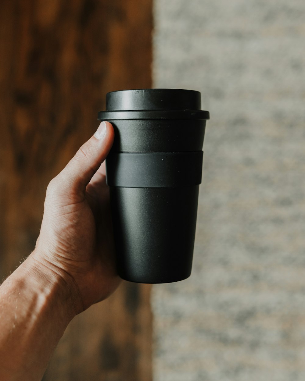 person holding black disposable cup