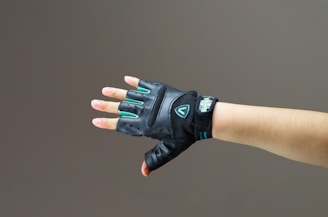 person wearing black and green leather fingerless gloves
