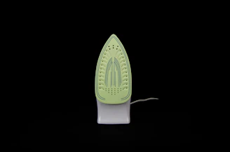 Close-up of a sleek, modern steam iron resting on a neatly folded shirt.