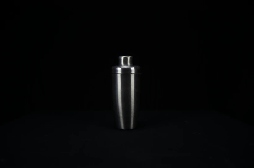 A sleek black and gold cocktail shaker mid-pour, capturing the shimmer of a luxury mixology experience.