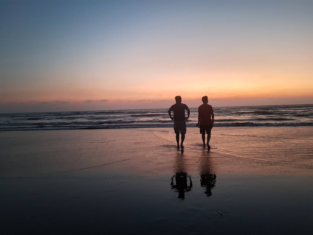 two people standing near seashore