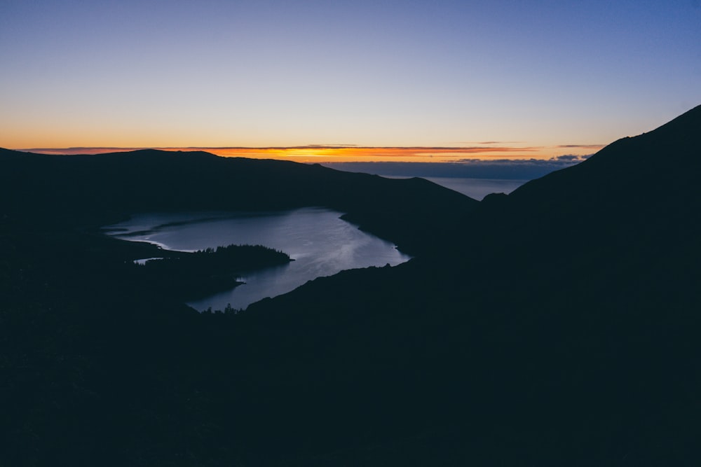 silhouette of hills near lake