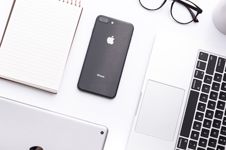 A neat workspace with a notebook, glasses, and a smartphone displaying a website mockup.