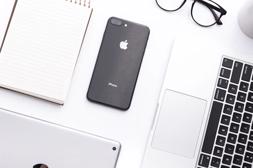 A cozy workspace with a MacBook, iPhone, and notepad ready for brainstorming.