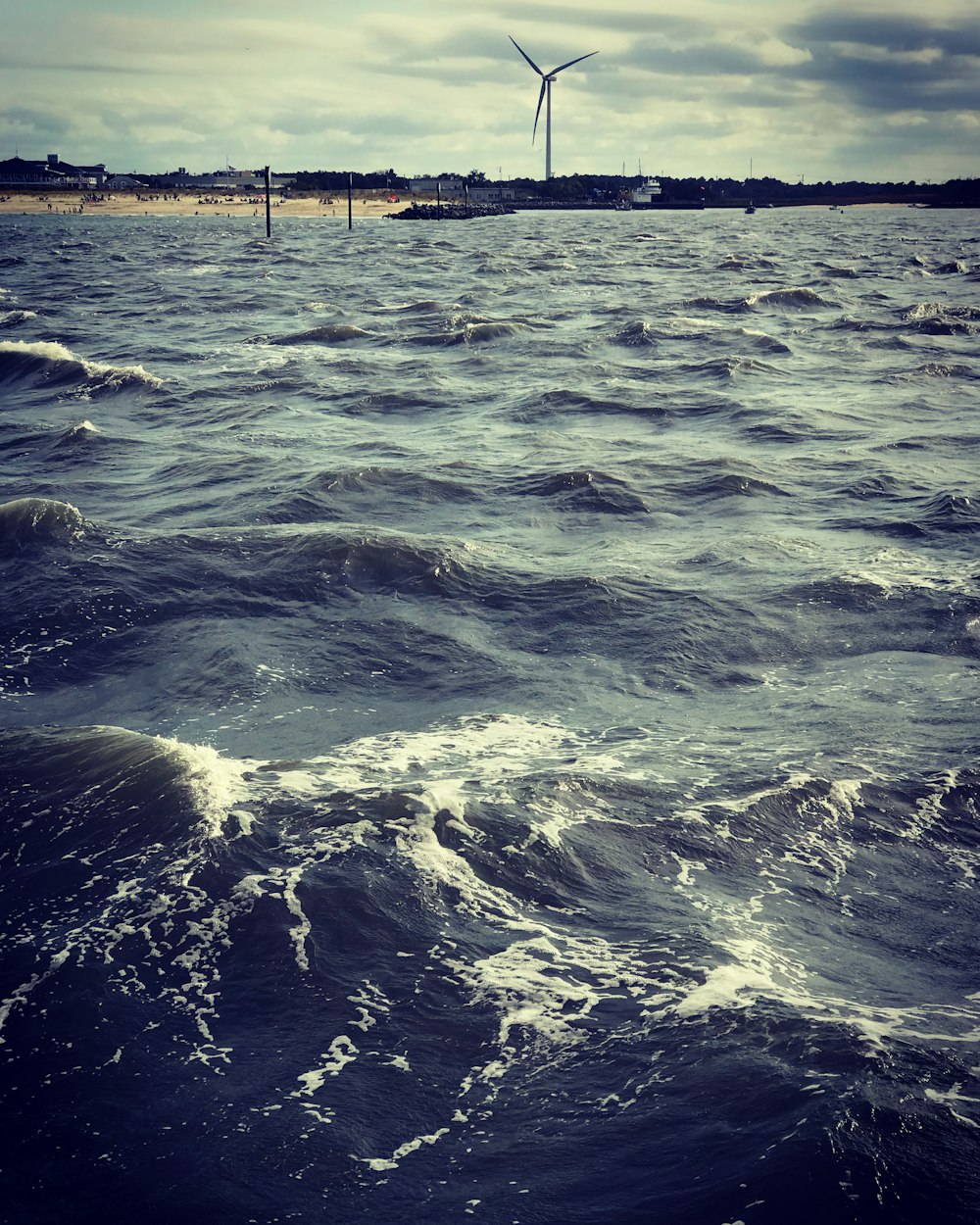 a wind turbine in the distance over a body of water