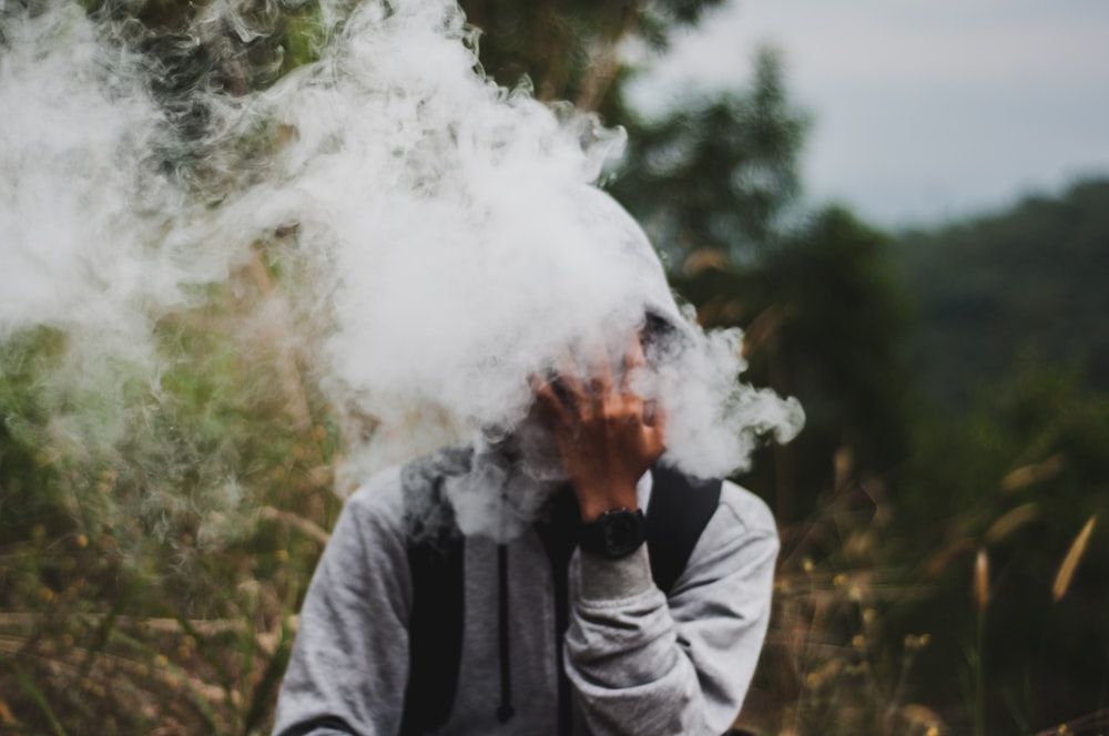 man covering his face with smoke