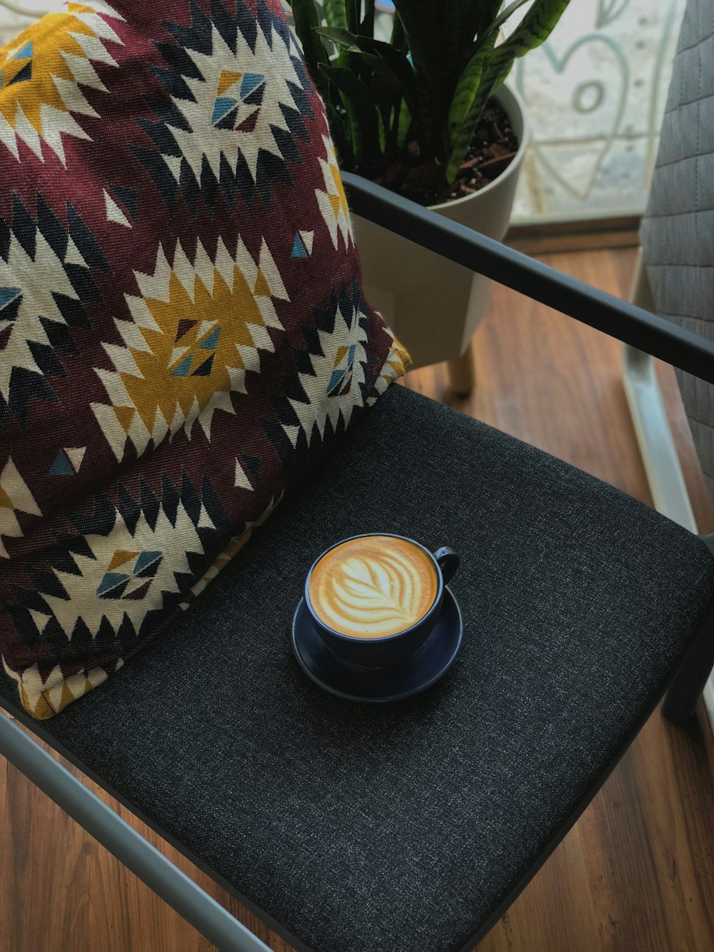 cup of latte on gray padded chair