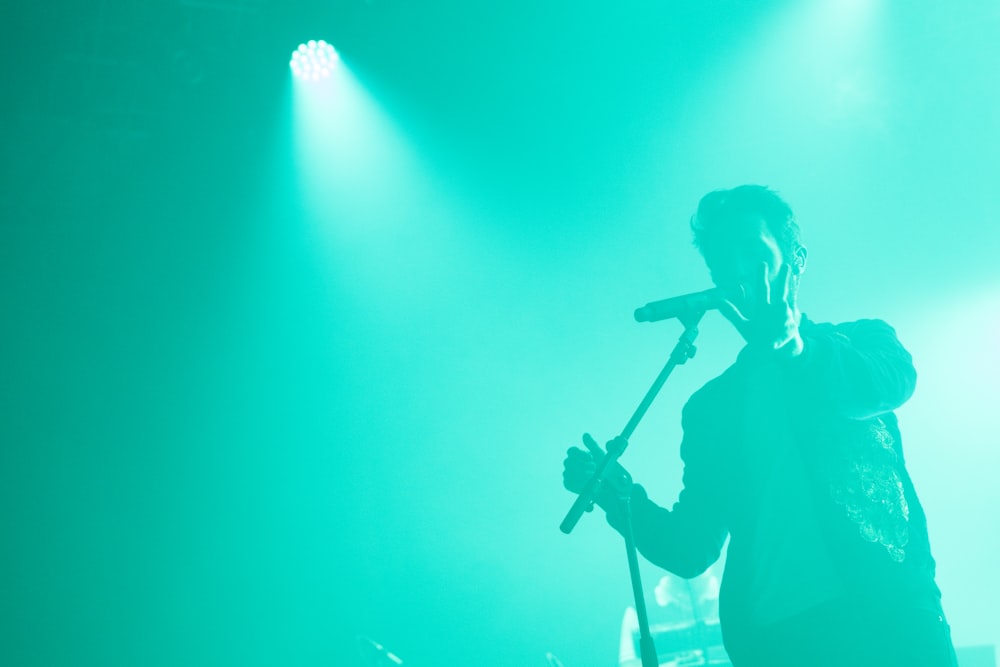 man raising his left hand holding microphone