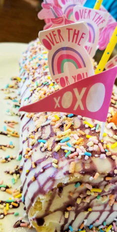 A vibrant cake with colorful sprinkles and a joyful birthday message in cursive.