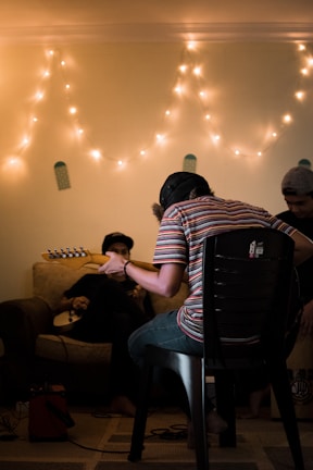person sitting on black chair playing guitar
