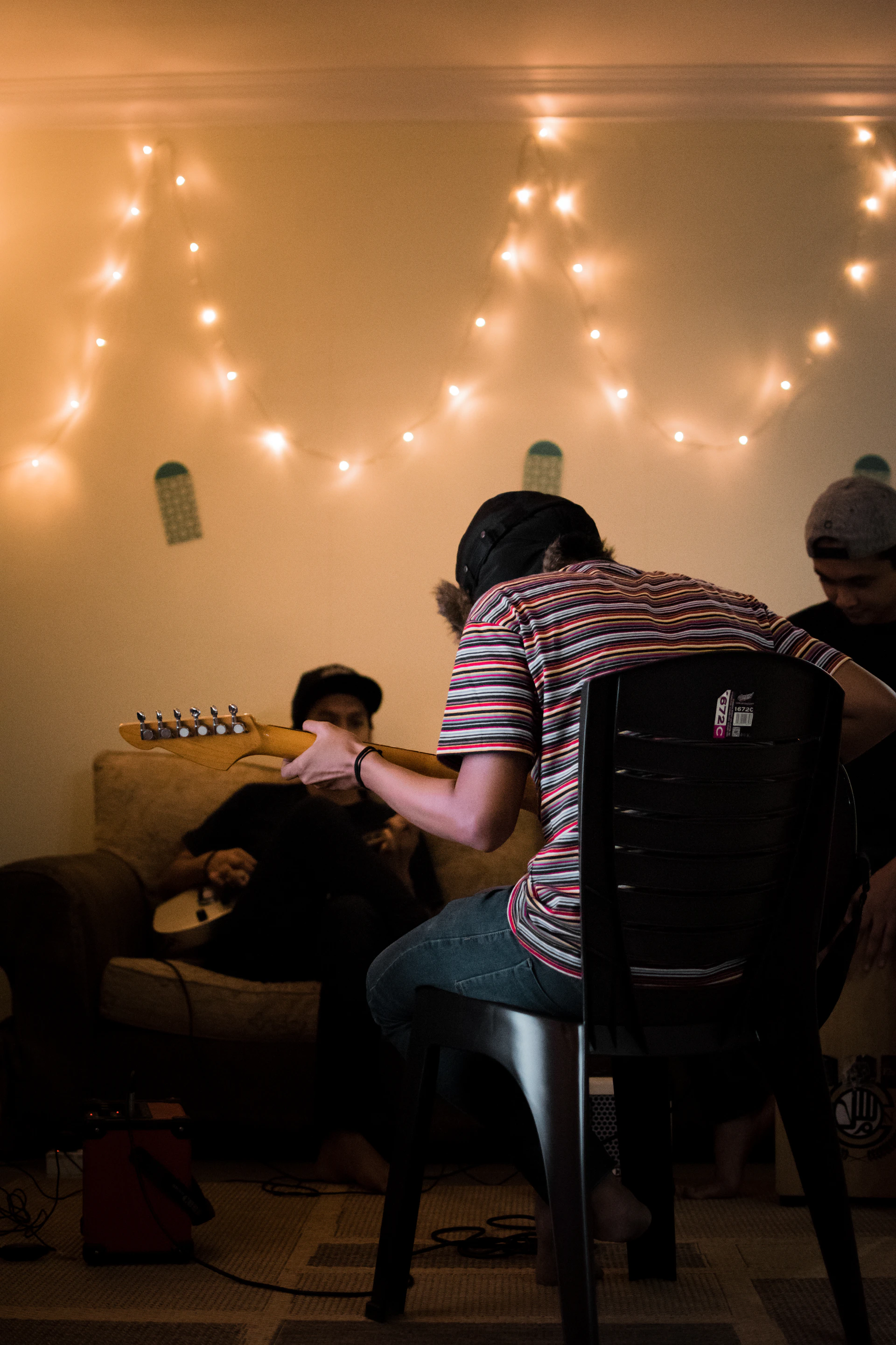 person sitting on black chair playing guitar