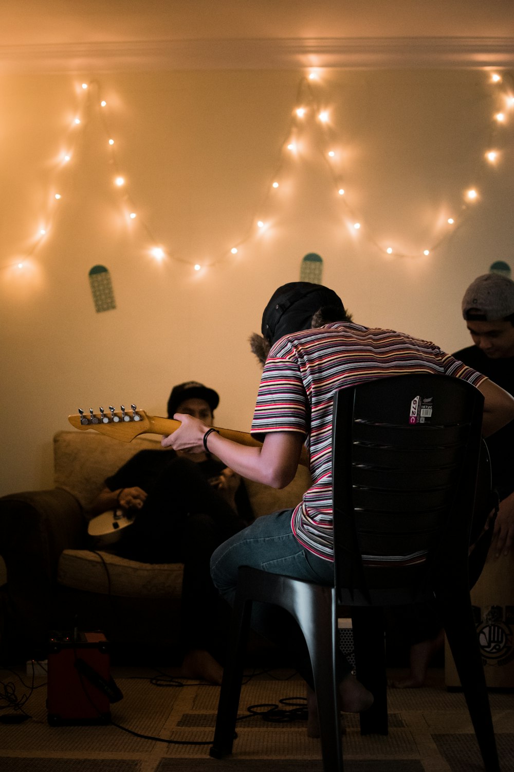 person sitting on black chair playing guitar