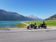 Smiling riders taking a break beside their Africa Twin and Tracer bikes near a scenic oasis.
