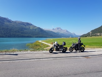 Smiling riders taking a break beside their Africa Twin and Tracer bikes near a scenic oasis.