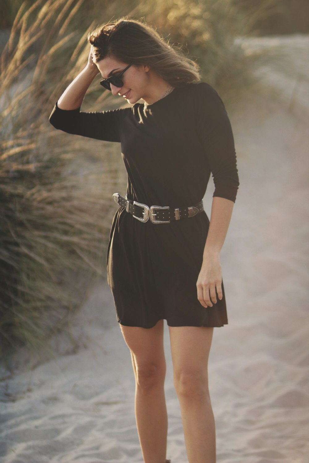 woman touching hair standing on sand