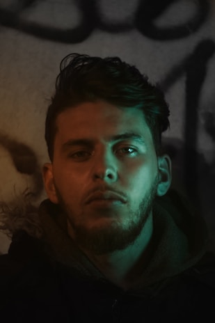 Portrait photo of a man with a dark background and bright green lighting accents.