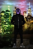Close-up of a model wearing a black mj originals hoodie with electric blue neon accents under city lights.