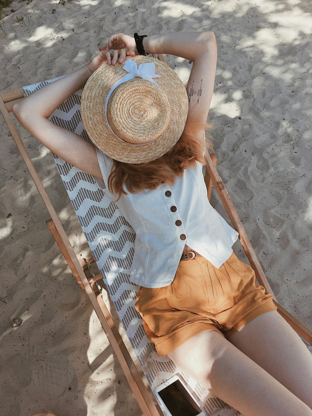 femme en haut blanc allongée sur une chaise