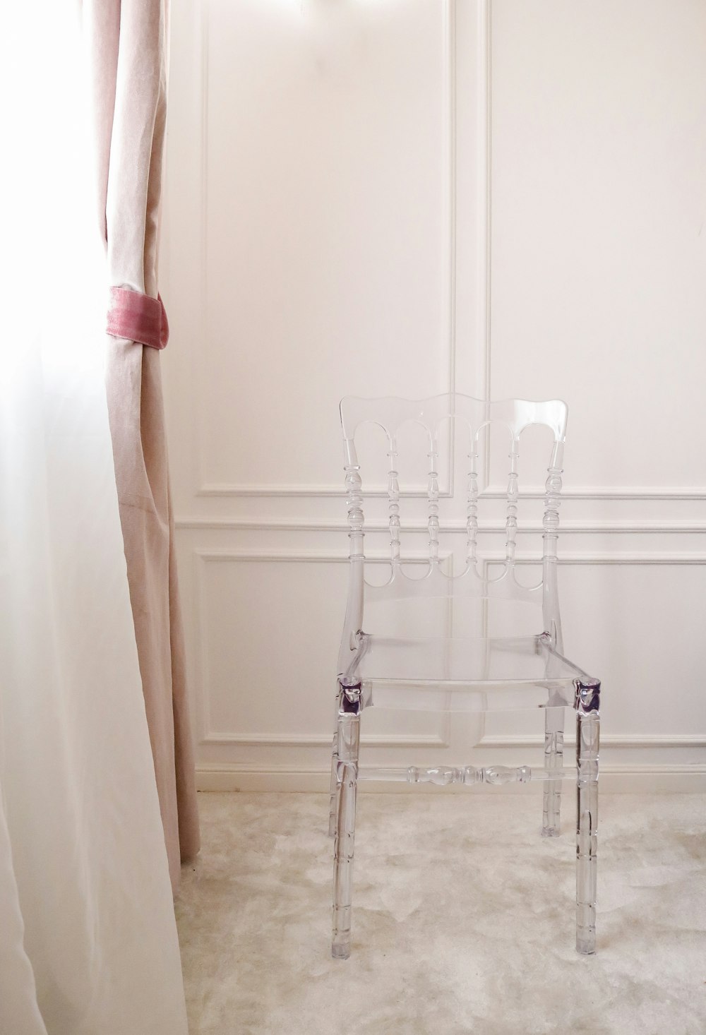 clear armless chair beside window