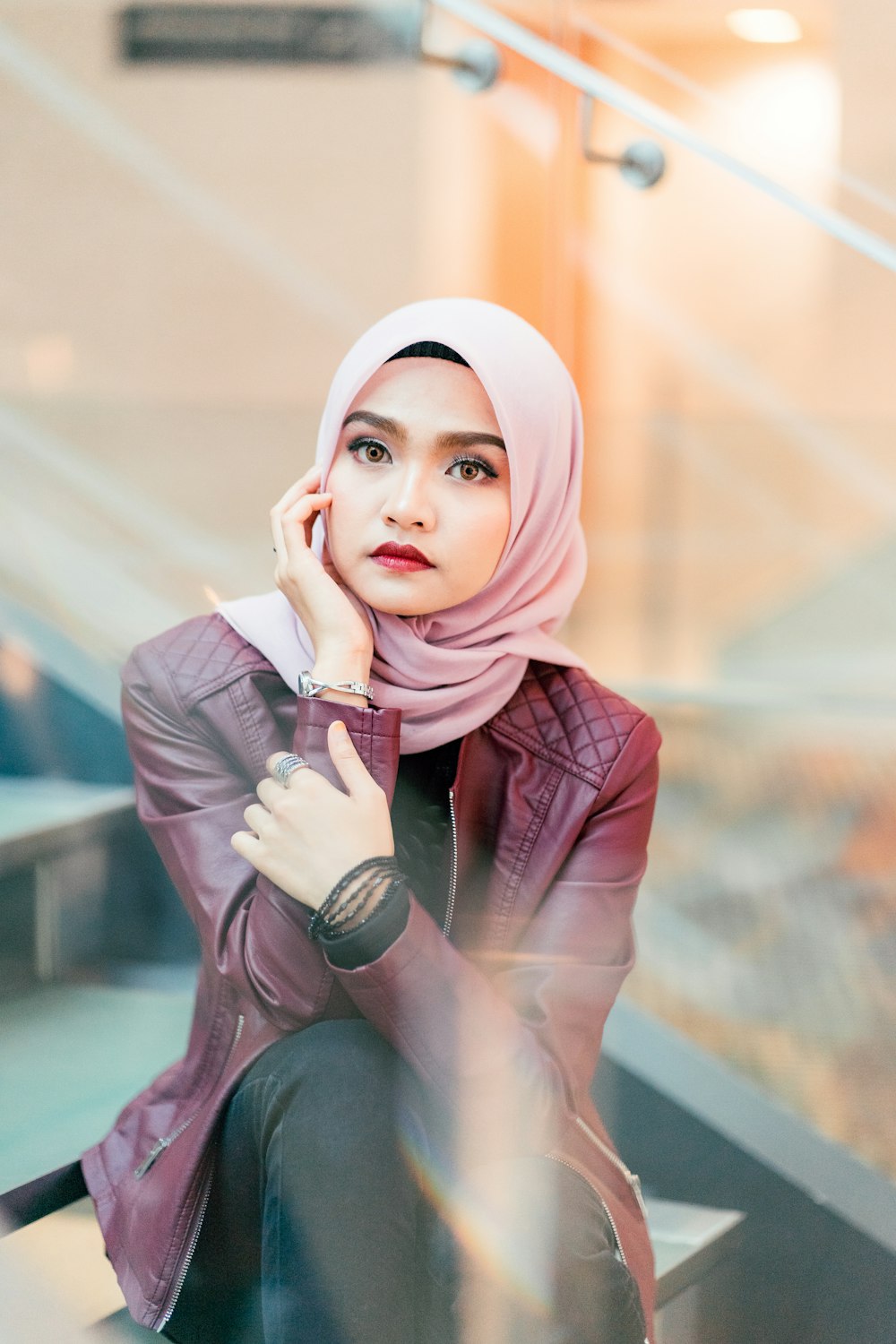 woman in maroon leather jacket sitting on stairs