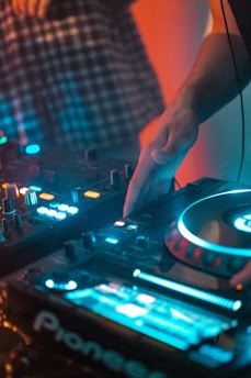 Close-up of hands mixing music on a modern DJ controller with colorful LED lights.