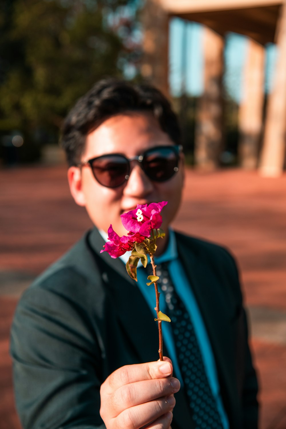 man holding red-petaled flowers