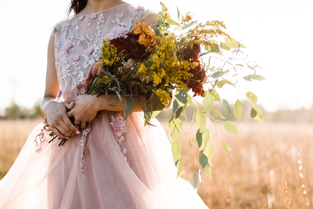 woman in pink and silver sleeveless dress holding bouquet of flowers