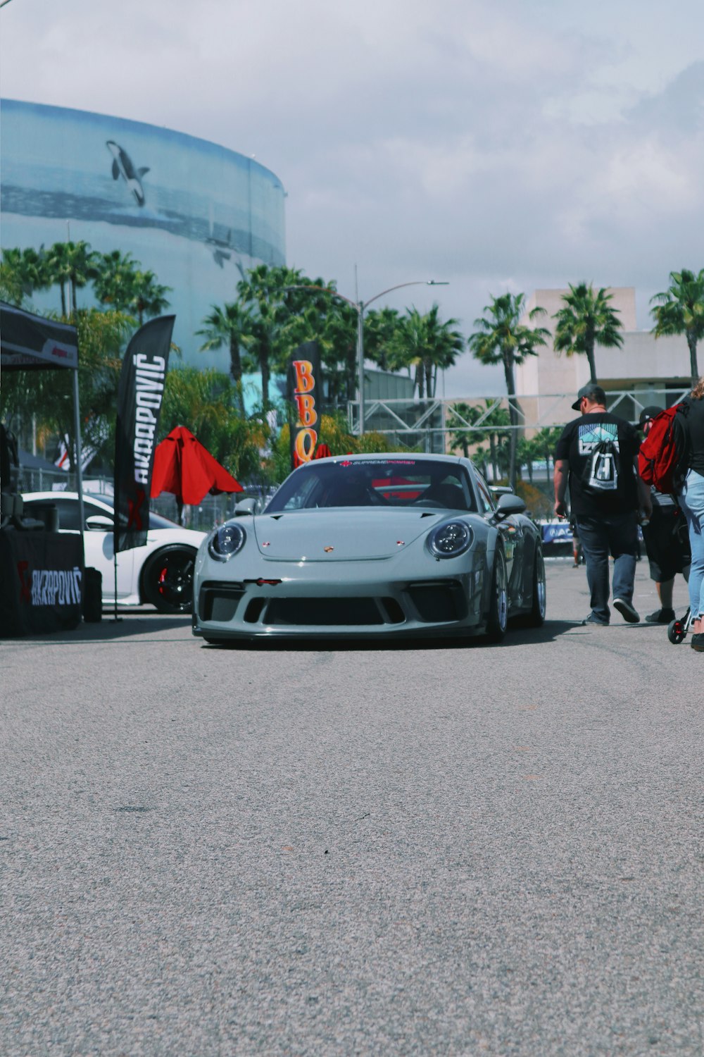 person standing beside gray luxury car