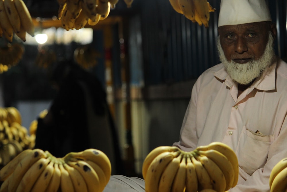 man in white dress shirt beside bunch of bananas