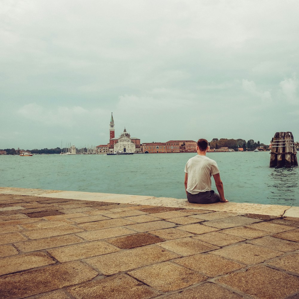 man sitting beside body of water