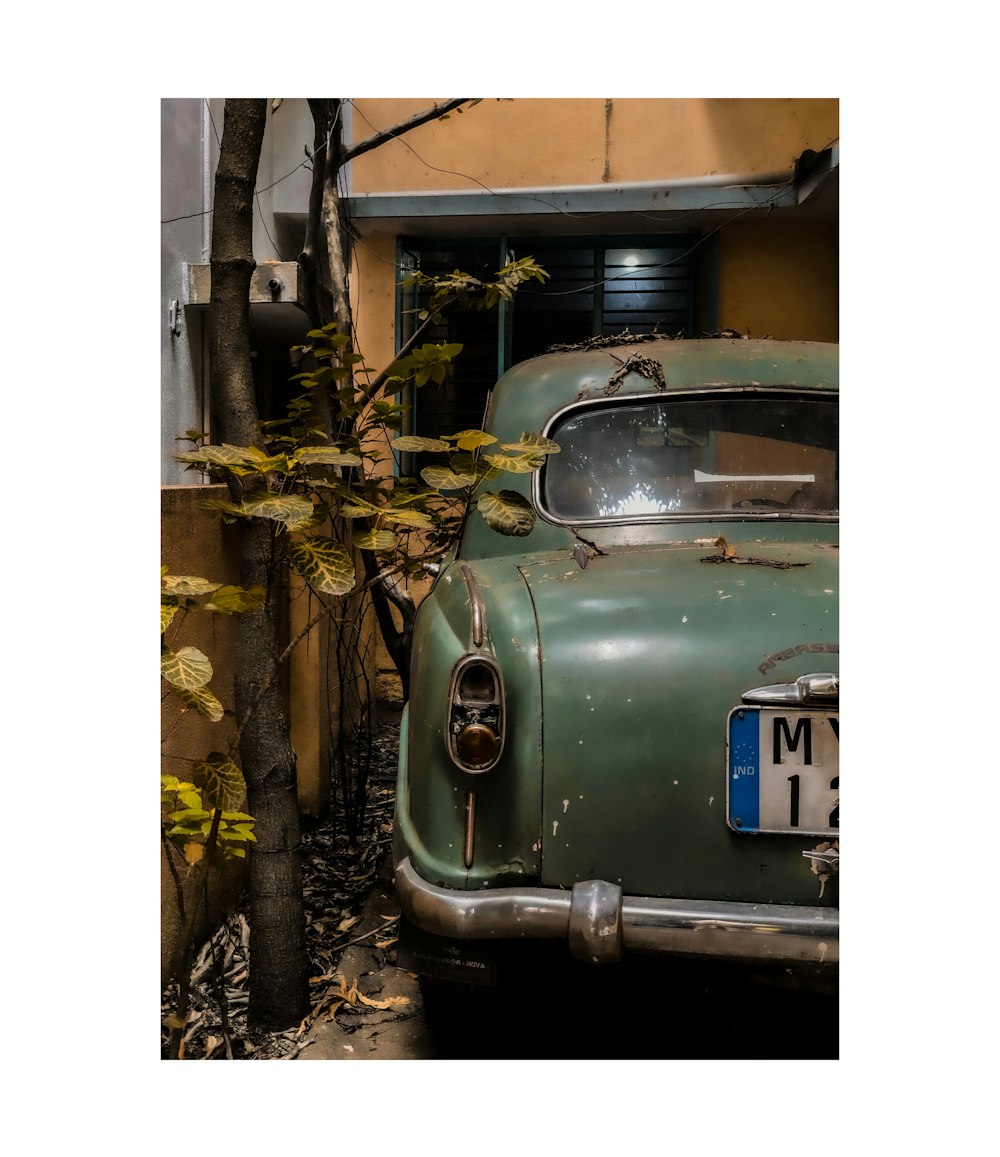 classic teal sedan parked beside wall