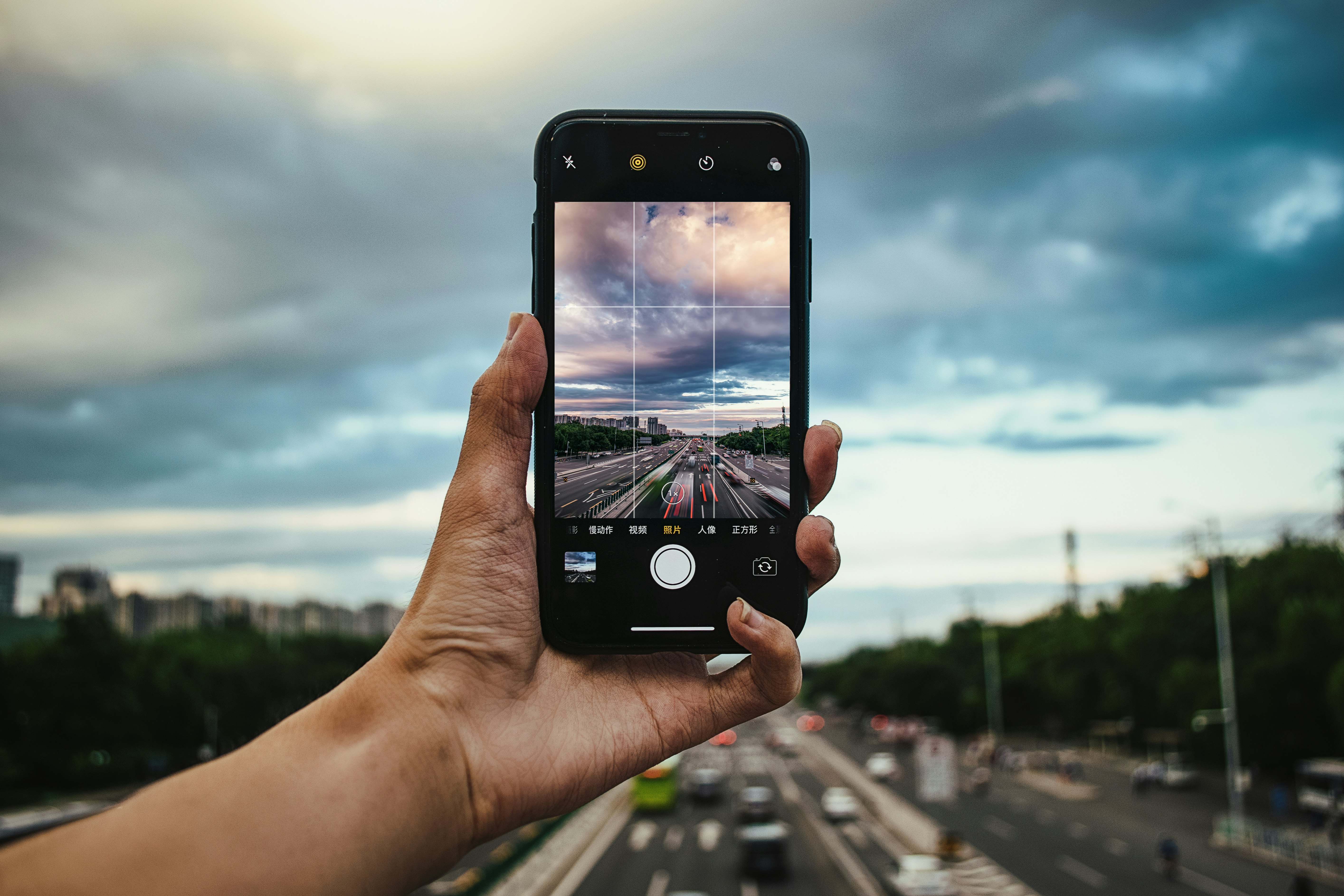 person taking photo of gloomy sky