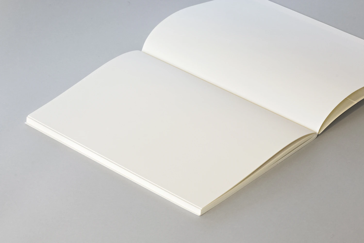 Raster 120 notebook lying open and flat on a grey bench — in stock
